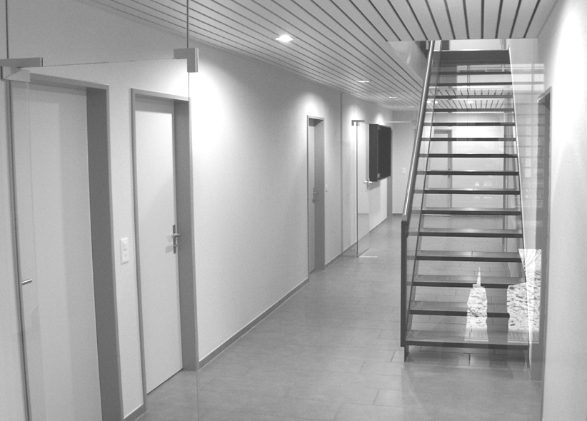 Heller Korridor mit Stahltreppe und Glasgeländer, schwarz-weiss
